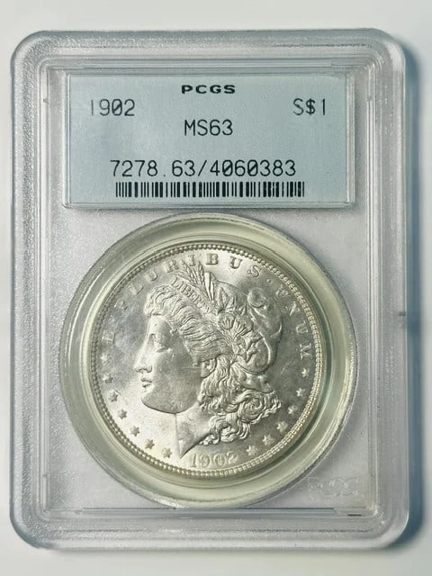 1902 Morgan Silver Dollar PCGS MS63 Green Holder: 1902 Morgan Silver Dollar PCGS MS63 Green Holder This 1902 Morgan Silver Dollar is graded MS-63 by PCGS and comes in the sought-after Old Green Holder. Struck at the Philadelphia Mint, this pre-owned 