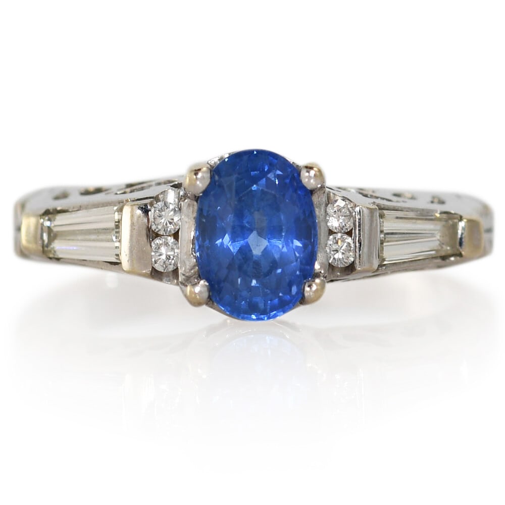 18K White Gold Sapphire Diamond Ring Size 5.5: 18K White Gold Sapphire Diamond Ring Size 5.5 This elegant ladies' ring features a natural oval blue sapphire weighing 1.12 carats, set in an 18K white gold setting. The sapphire is complemented by ba