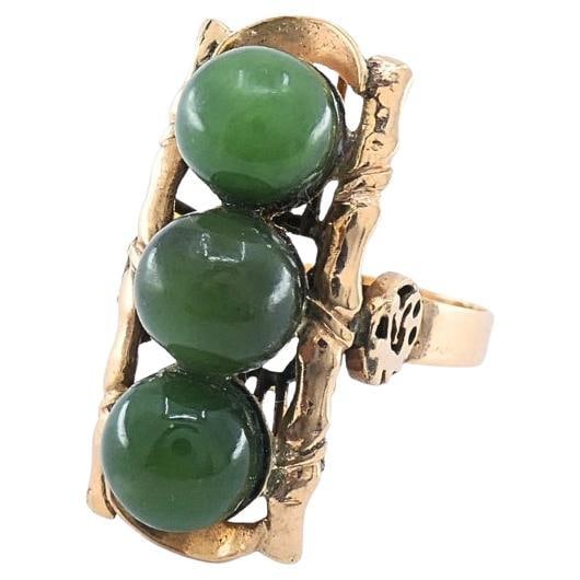Mid Century 14k Gold Jade 3 Stone Bamboo Motif Ring: Mid Century 14k Gold Jade 3 Stone Bamboo Motif Ring Vintage mid-20th century cocktail ring in 14k gold featuring a vertical row of three green cabochon jade stones in a stylized bamboo motif. The elon