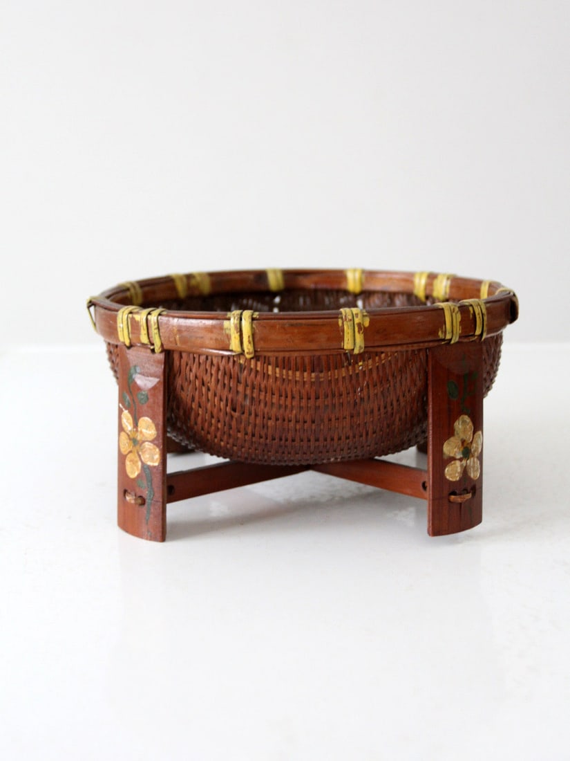 Vintage Hand Painted Footed Basket with Floral Motifs: Vintage Hand Painted Footed Basket with Floral Motifs This vintage hand-painted footed basket showcases a beautifully woven design complemented by sturdy wooden feet adorned with delicate floral motif