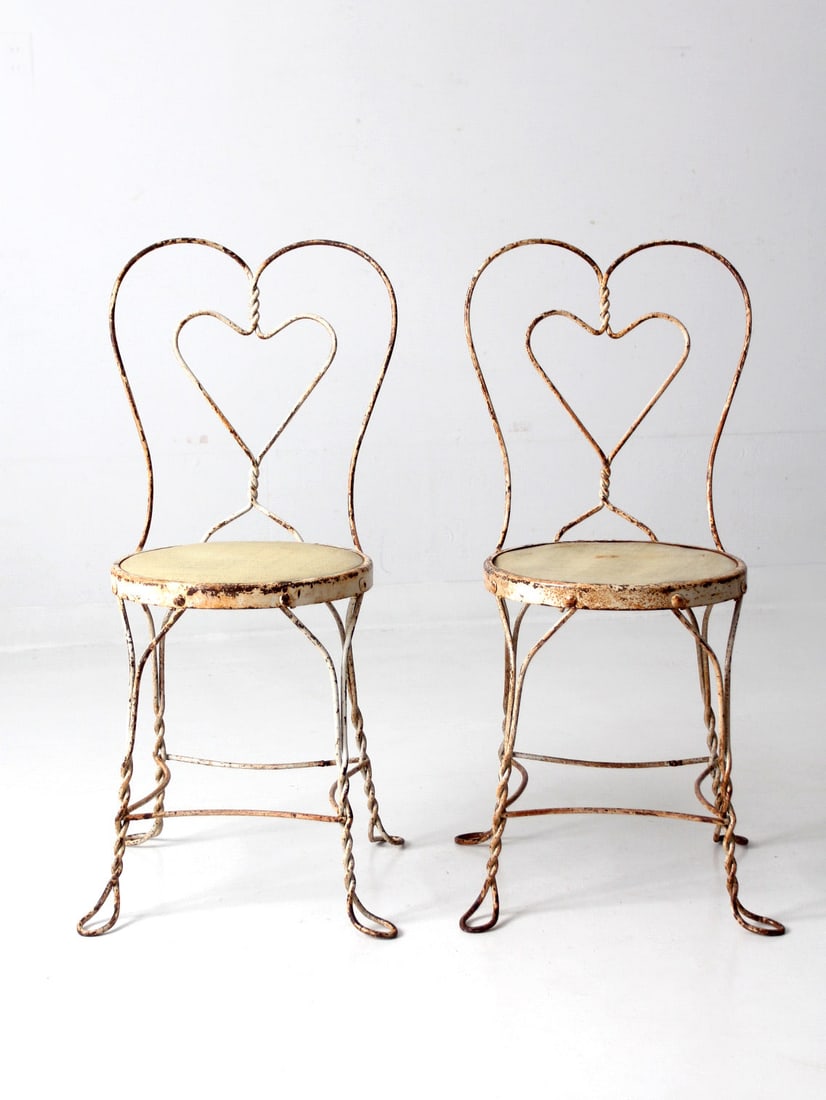 Vintage Wrought Iron Ice Cream Parlor Chairs Pair with Heart Design: Vintage Wrought Iron Ice Cream Parlor Chairs Pair with Heart Design This charming pair of early 20th century ice cream parlor chairs is crafted from painted wrought iron. Each chair showcases a classi