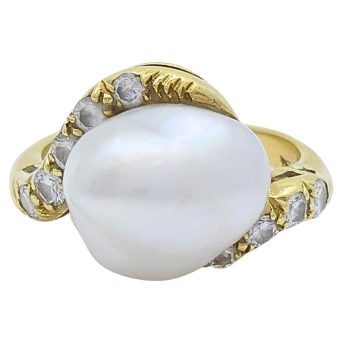 1970s Baroque Pearl Diamond Ring in 18k Yellow Gold Size 6.75: 1970s Baroque Pearl Diamond Ring in 18k Yellow Gold Size 6.75 Vintage 18k yellow gold ring featuring a baroque pearl accented by round-cut diamonds in an asymmetric bypass design. The center pearl ris