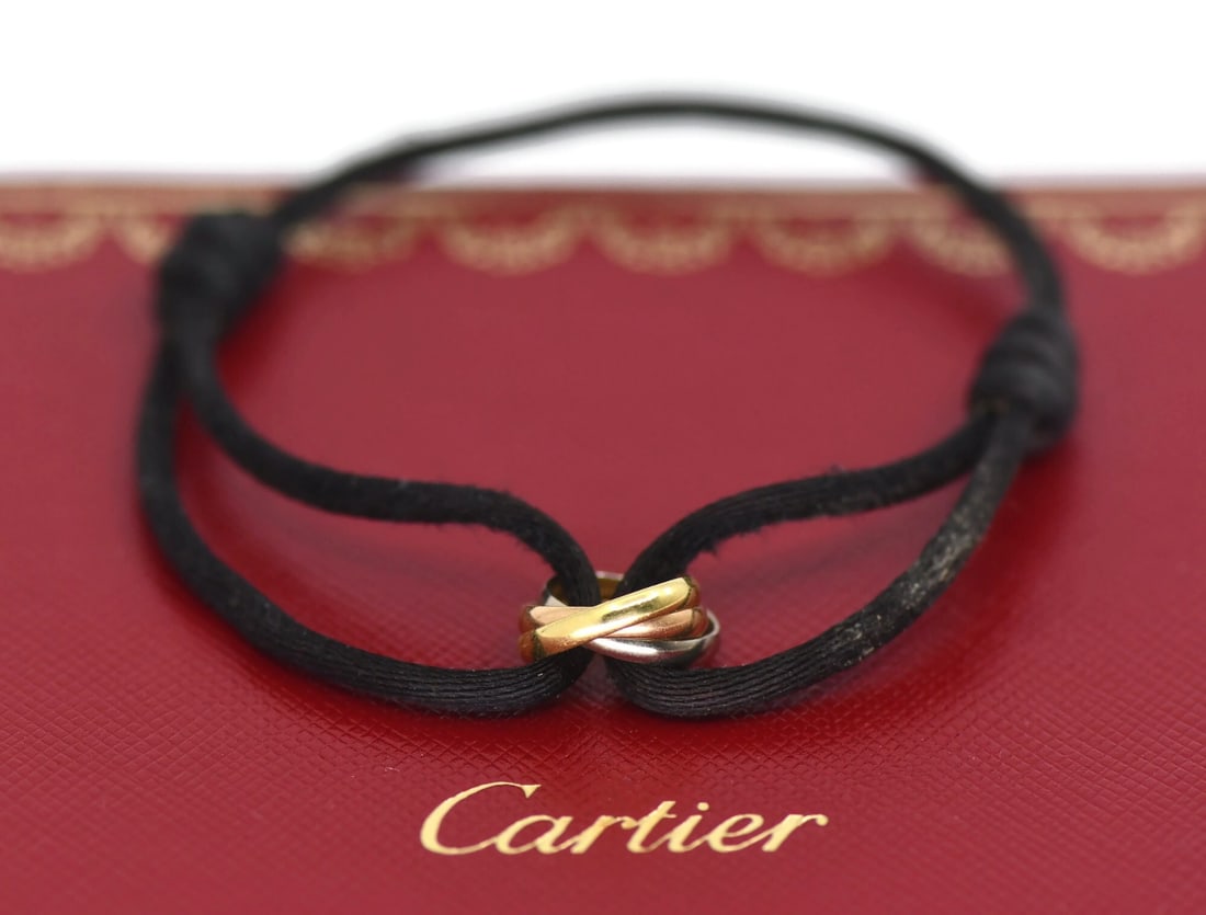 Cartier Trinity multi-tone 18k gold bracelet with pouch certificate: Cartier Trinity multi-tone 18k gold bracelet with pouch certificate A pre-owned Cartier Trinity string bracelet in 18K multi-tone gold with a chain style and no main stone. It is stated to be made in 