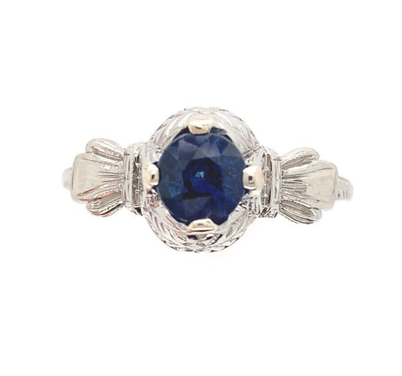 Art Deco 18k White Gold .79ct Blue Sapphire Hand Engraved Ring: Art Deco 18k White Gold .79ct Blue Sapphire Hand Engraved Ring Experience the elegance of the Art Deco era with this exquisite 18k white gold ring featuring a genuine round sapphire. Weighing .79ct, t
