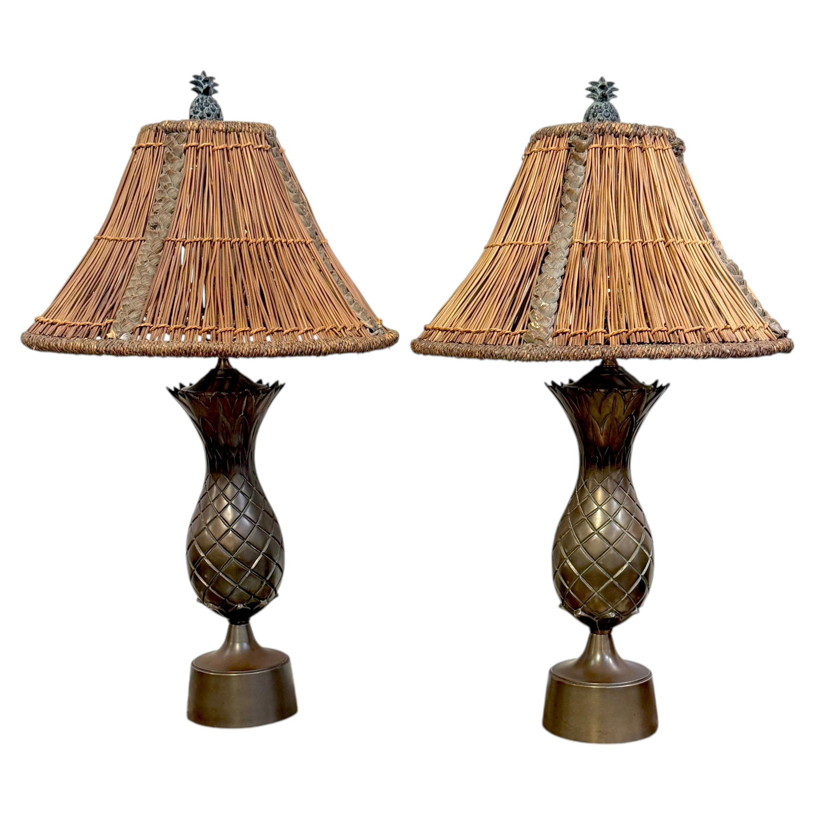 Bronze Pineapple Table Lamps Pair with Rattan Shades: Bronze Pineapple Table Lamps Pair with Rattan Shades This pair of coastal bronze pineapple table lamps features a sculptural pineapple motif, symbolizing hospitality and luxury, in the British Colonia
