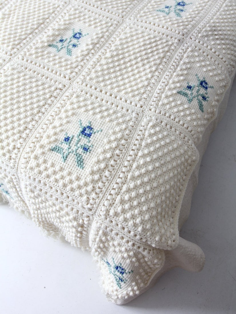 Vintage Cream Knit Blanket with Floral Pattern and Fringe: Vintage Cream Knit Blanket with Floral Pattern and Fringe Experience warmth and nostalgia with this vintage knit blanket. Crafted in a soothing cream hue, it showcases charming bobble knit squares ado