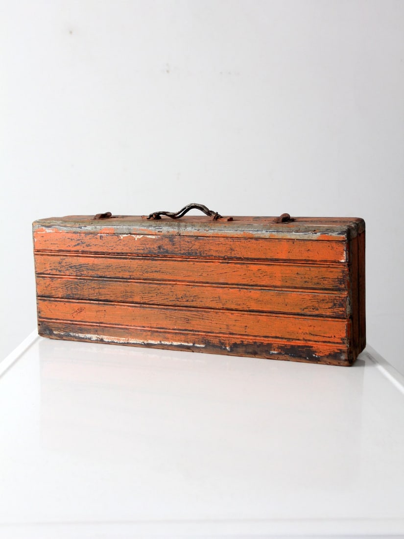 Vintage Orange Wooden Toolbox with Leather Handle: Vintage Orange Wooden Toolbox with Leather Handle This vintage wooden toolbox showcases a slender beadboard design in a striking orange finish complemented by black accents. The aged leather handle ad