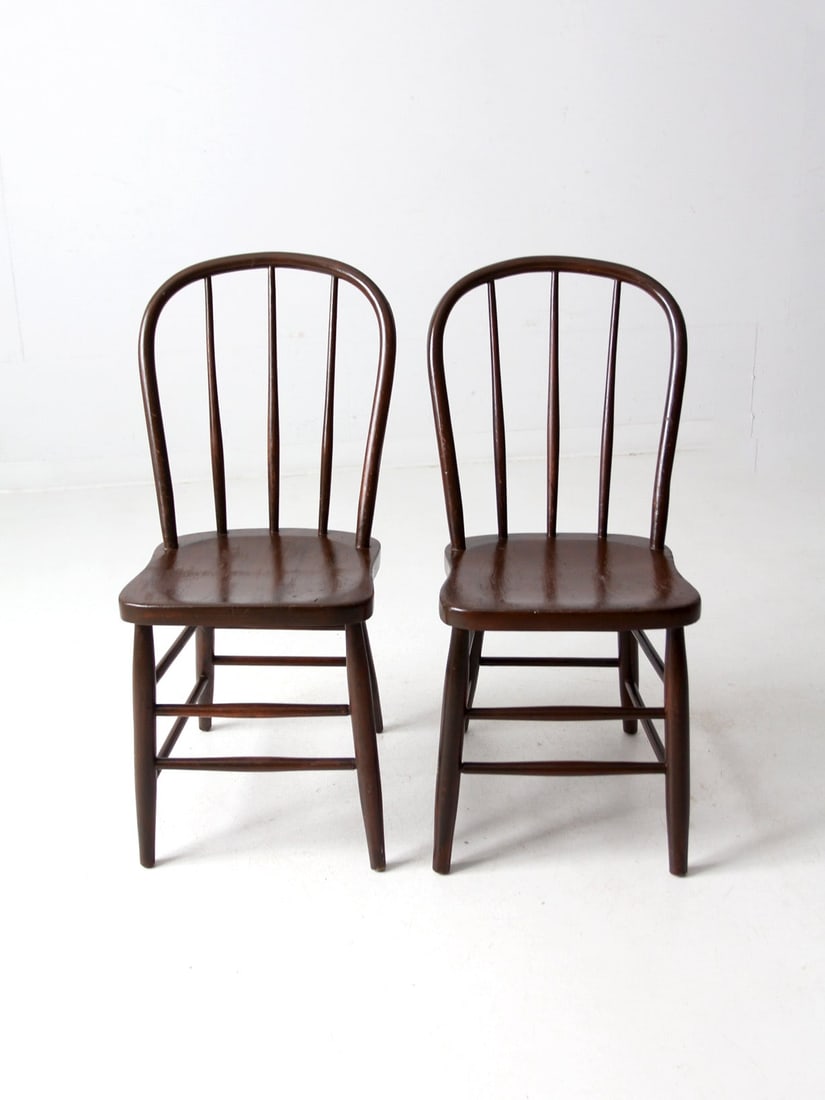 Pair of Antique Windsor Bow Back Dining Chairs: Pair of Antique Windsor Bow Back Dining Chairs This pair of antique wooden Windsor bow back dining chairs showcases classic design elements, including elegantly turned spindles, legs, and stretchers. 