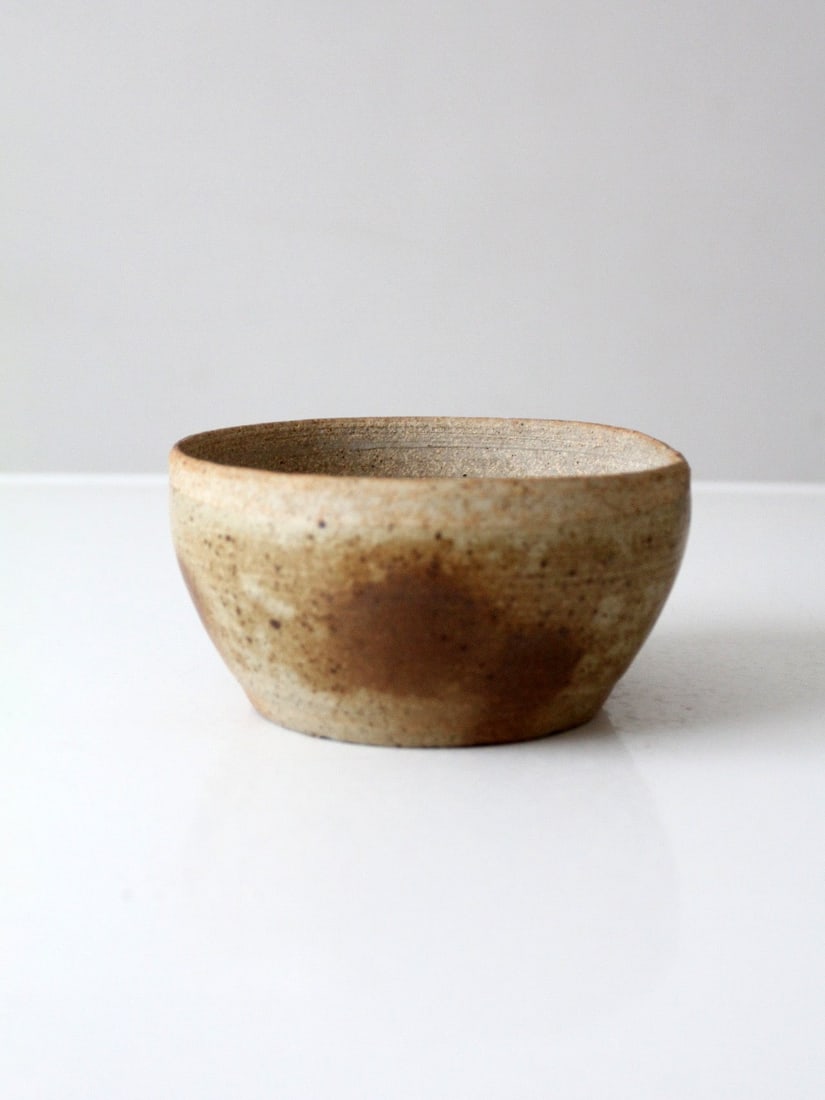 Vintage Tan Brown Glazed Studio Pottery Bowl: Vintage Tan Brown Glazed Studio Pottery Bowl This vintage handmade studio pottery bowl features an organic form and a softly varied tan glaze accented with warm brown tones. Its understated design mak