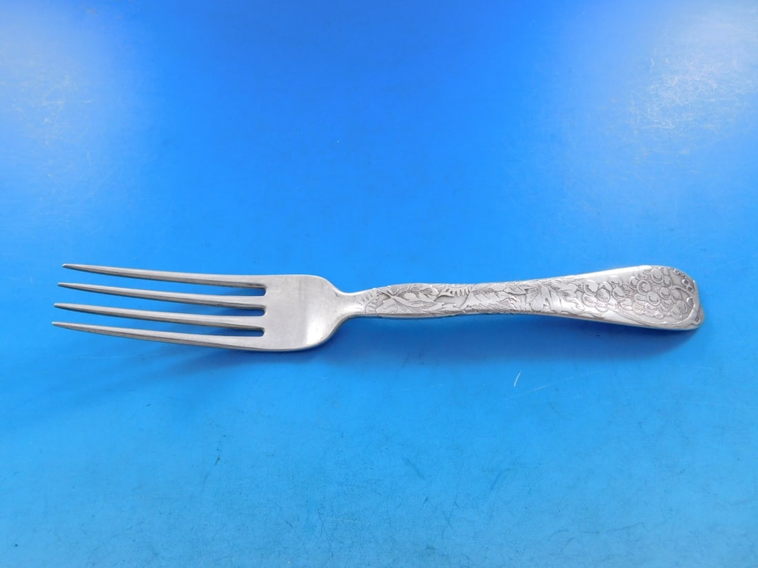 Tiffany Sterling Silver Fork Lap Over Edge Grape Motif 7 1/4": Tiffany Sterling Silver Fork Lap Over Edge Grape Motif 7 1/4" This exquisite sterling silver fork from Tiffany & Co. features the elegant Lap Over Edge pattern, showcasing a beautiful grape motif. Mea