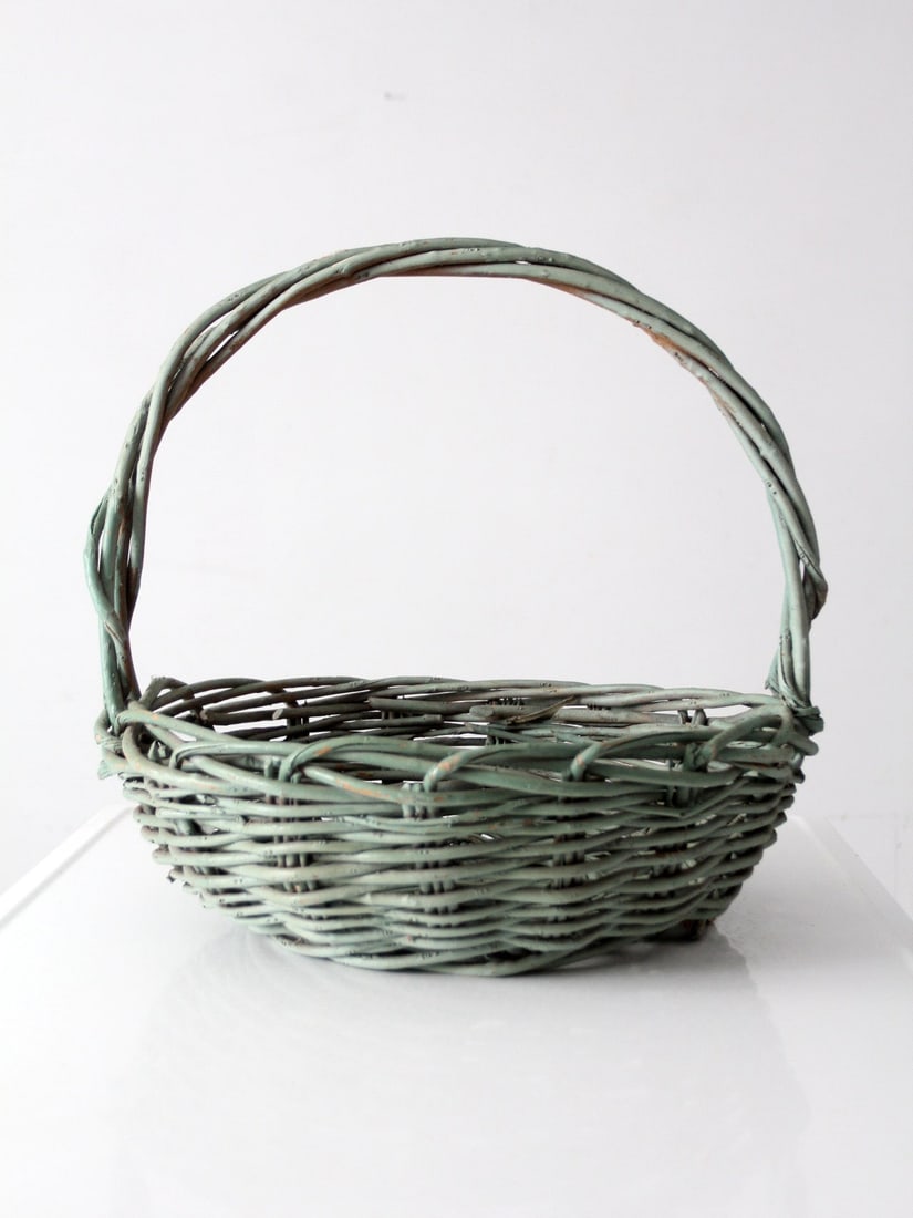 Large Green Painted Woven Basket with Twisted Handle: Large Green Painted Woven Basket with Twisted Handle This vintage gathering basket features a wide, low profile with a distinctive twisted handle that arches gracefully across the top. The green paint