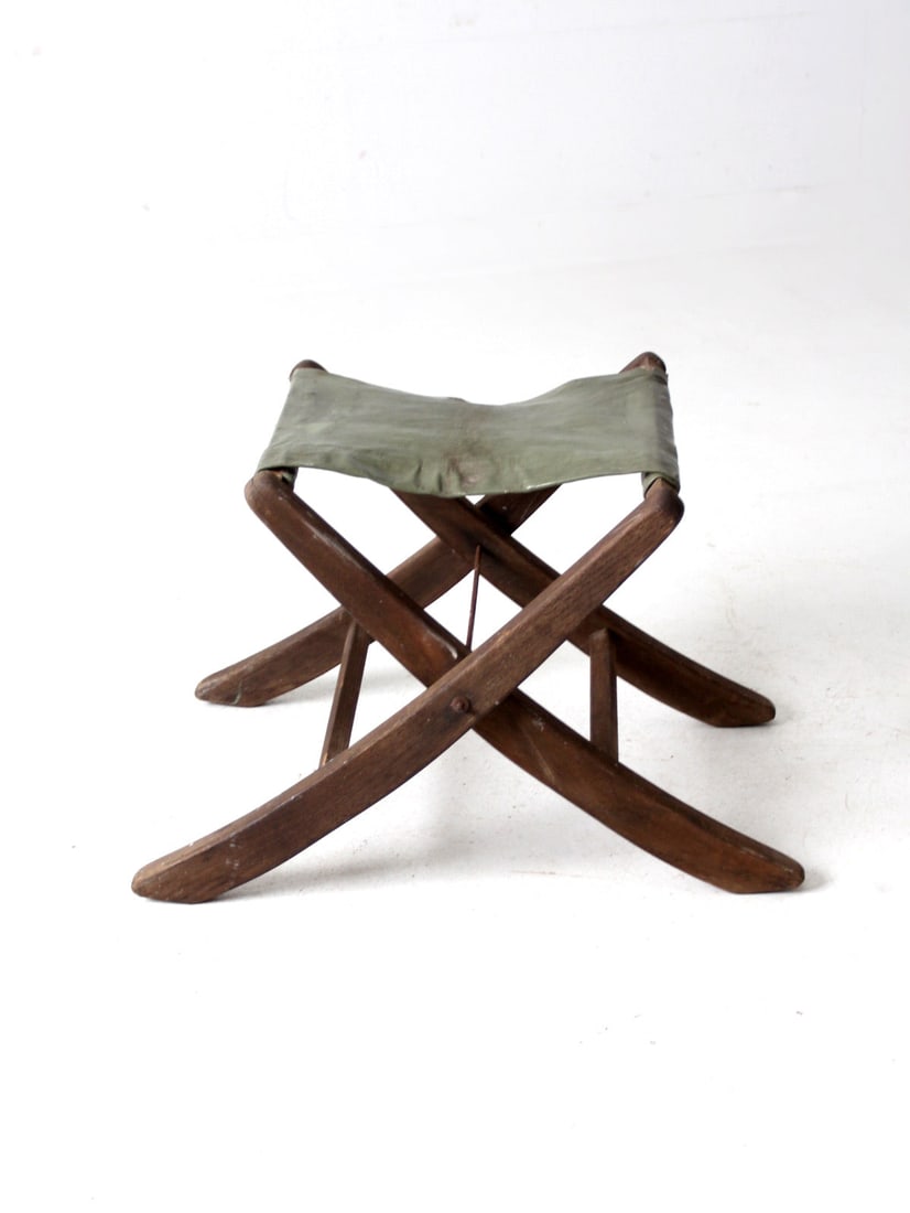 Mid-Century Folding Camp Stool with Olive Green Patent Leather Seat: Mid-Century Folding Camp Stool with Olive Green Patent Leather Seat Discover this charming mid-20th century Vintage Camp Stool, designed with a unique splay leg configuration. This folding stool featu
