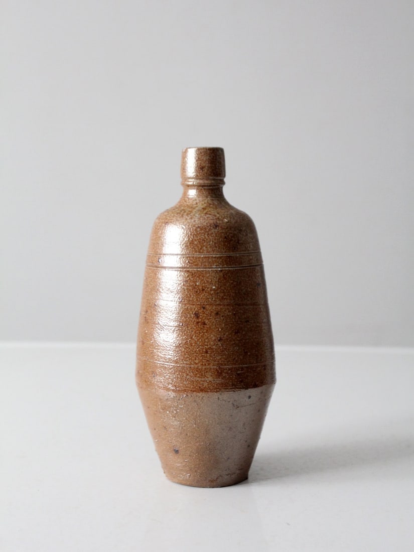 Brown Glazed Bottleneck Studio Pottery Vase 9.5 in: Brown Glazed Bottleneck Studio Pottery Vase 9.5 in This vintage handmade studio pottery vase showcases a tall, tapered silhouette with a narrow bottleneck opening. The vase features a warm brown glaze