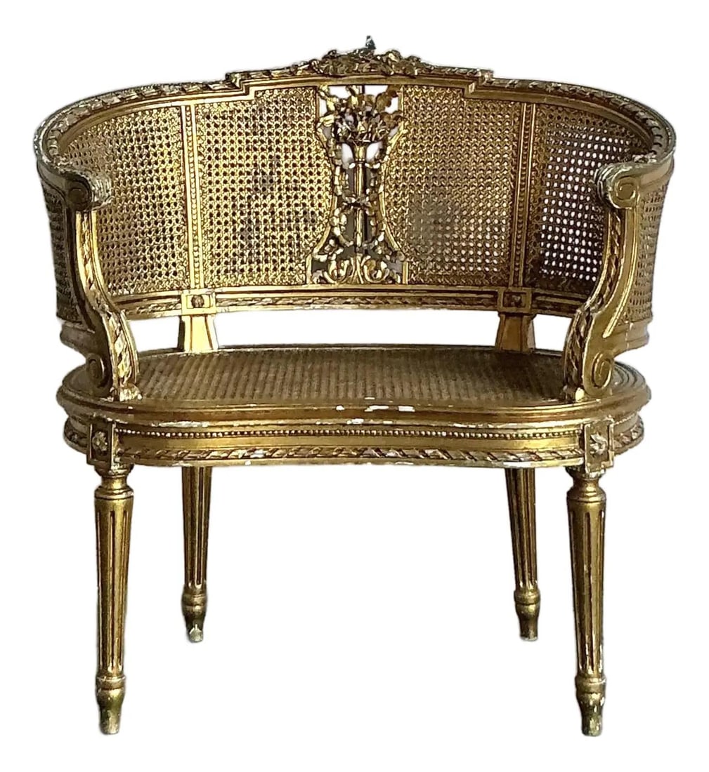 Louis XVI Style Giltwood Caned Corner Chair with Heavy Patina: Louis XVI Style Giltwood Caned Corner Chair with Heavy Patina This vintage Regency gilt caned chair showcases classic Louis XVI style with a graceful curved barrel back, airy cane webbing, and a centr