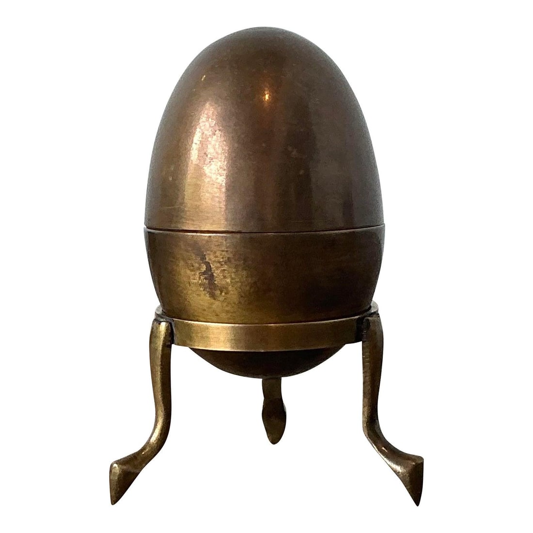 Brass Egg Trinket Box on Tripod Stand: Brass Egg Trinket Box on Tripod Stand This vintage brass egg trinket box features a sculptural ovoid design and sits on a minimalist tripod stand with pointed feet. Crafted from solid brass, it showca