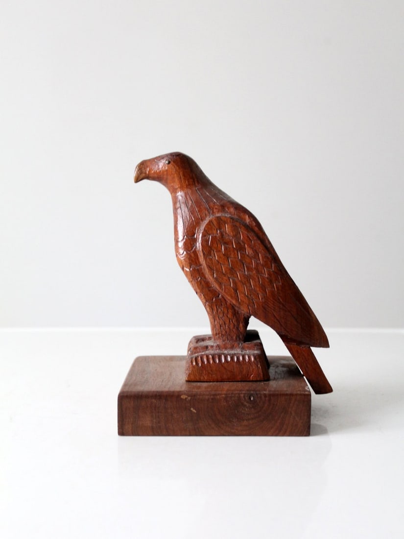 American Folk Art Carved Wood Eagle Figure on Base: American Folk Art Carved Wood Eagle Figure on Base Vintage hand-carved wood eagle sculpture with deeply incised feather detailing, brass tack eyes, and a rich brown finish. The stylized eagle rests on