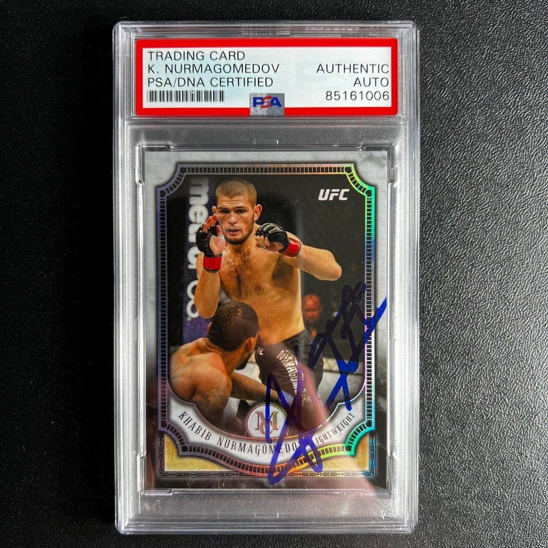 PSA Encapsulated Khabib Nurmagomedov Autographed 2018 Prizm Card #18: PSA Encapsulated Khabib Nurmagomedov Autographed 2018 Prizm Card #18 This is a 2018 Panini Prizm #18 sports trading card featuring Khabib Nurmagomedov. The card is signed by Khabib Nurmagomedov and ha