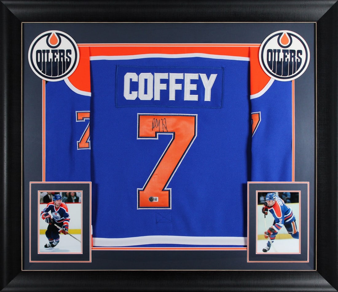 Framed Blue Pro Style Jersey Signed by Paul Coffey BAS BU16652: Framed Blue Pro Style Jersey Signed by Paul Coffey BAS BU16652 Professionally framed blue pro style jersey signed by Paul Coffey and associated with the Edmonton Oilers. This original autograph is aut
