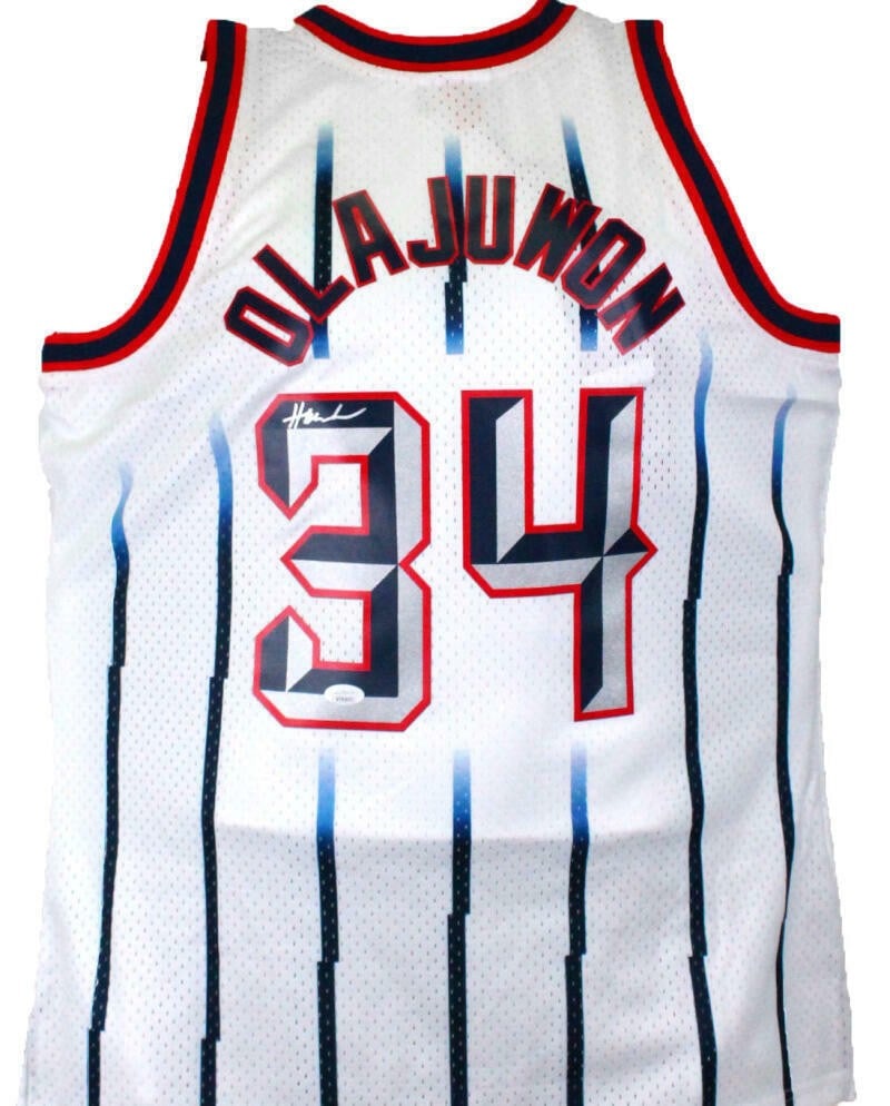 Mitchell and Ness Hardwood Classic Swingman Rockets Jersey Signed by Hakeem Olajuwon: Mitchell and Ness Hardwood Classic Swingman Rockets Jersey Signed by Hakeem Olajuwon This is an original Hakeem Olajuwon signed basketball jersey in a white Hardwood Classics Swingman style. It is pre