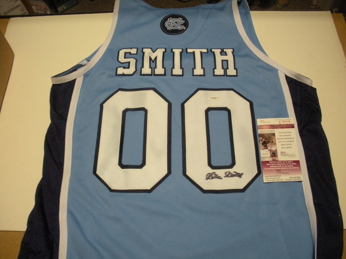Dean Smith Signed North Carolina Colosseum Jersey with JSA COA: Dean Smith Signed North Carolina Colosseum Jersey with JSA COA This official licensed North Carolina basketball jersey, signed by Dean Smith, is a remarkable collectible for any sports enthusiast. Fea