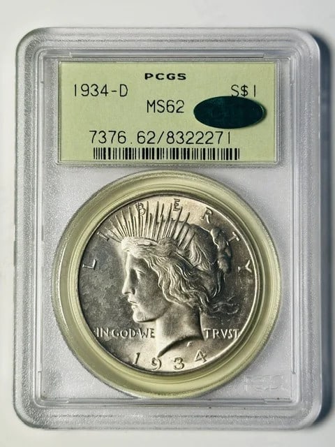 1934 D Silver Dollar PCGS MS62 CAC Certified: 1934 D Silver Dollar PCGS MS62 CAC Certified 1934-D Peace Dollar certified by PCGS as MS 62 and approved by CAC. This silver dollar is presented in an old green holder and is offered in pre-owned cond