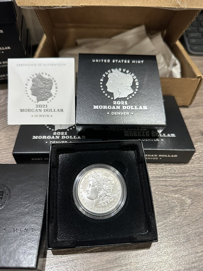 2021-D Morgan Silver Dollar with OGP and COA Denver Mint: 2021-D Morgan Silver Dollar with OGP and COA Denver Mint This 2021-D Morgan Silver Dollar showcases a remarkable design rooted in American history. Crafted from 99.9% pure silver, this coin carries a 