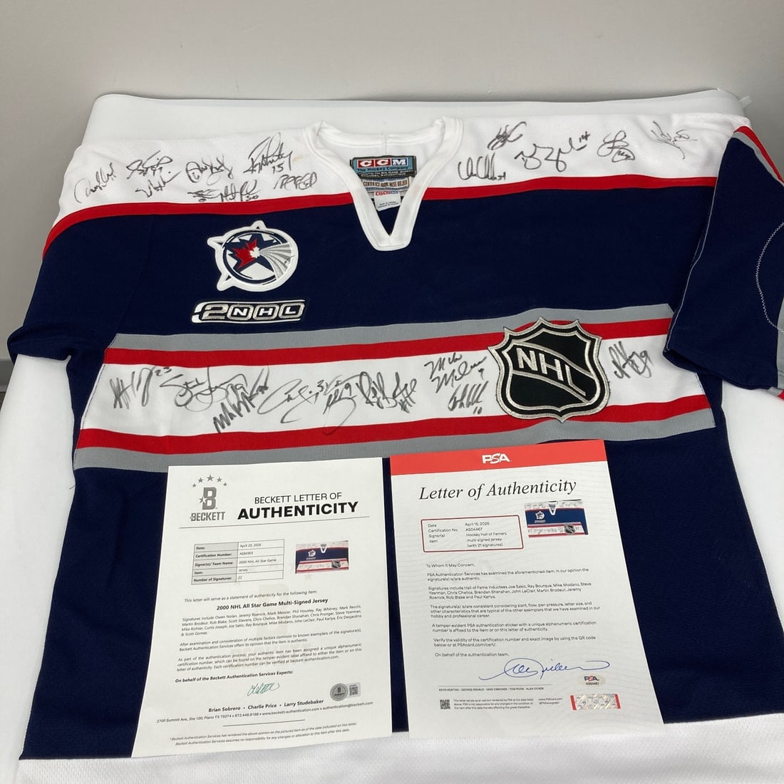 Authentic 2000 NHL All Star Game Multi Signed Hockey Jersey PSA DNA Beckett LOA: Authentic 2000 NHL All Star Game Multi Signed Hockey Jersey PSA DNA Beckett LOA Authentic 2000 NHL All-Star Game hockey jersey signed by multiple players in bold black felt tip. Named signers include 