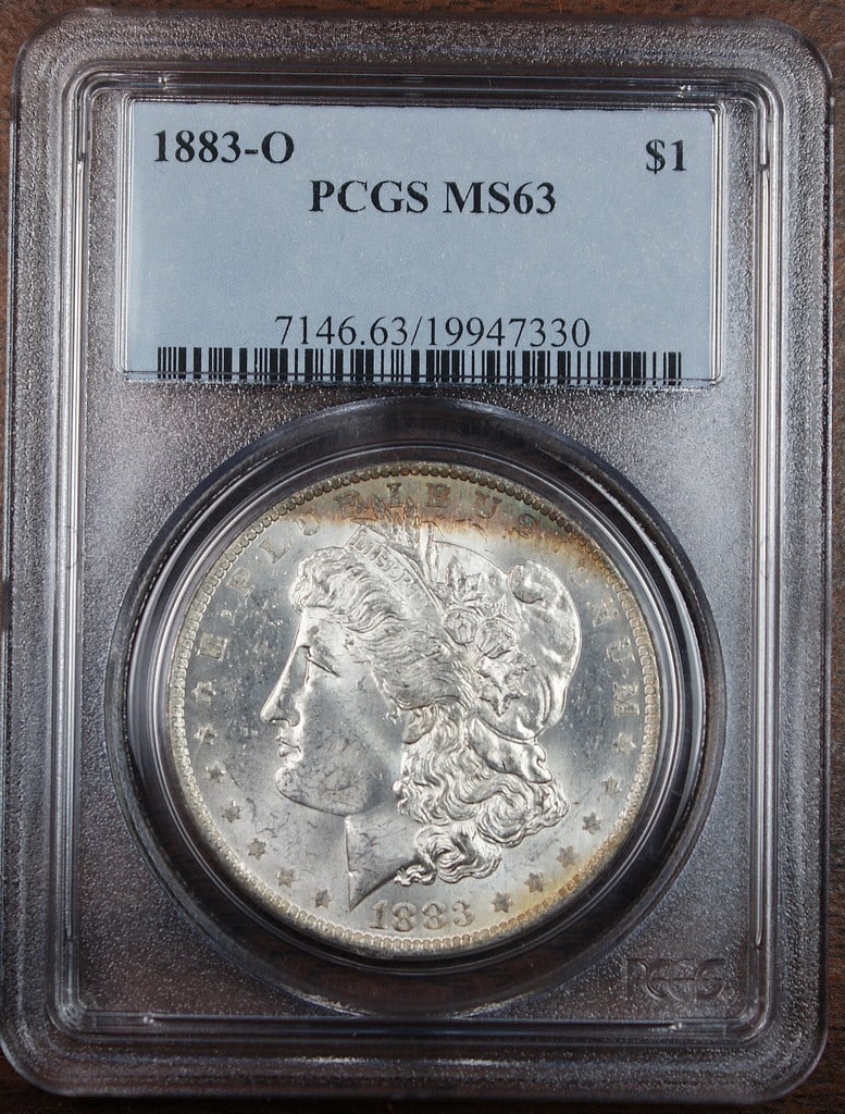 PCGS MS63 1883 O Morgan Silver Dollar New Orleans Mint: PCGS MS63 1883 O Morgan Silver Dollar New Orleans Mint 1883-O Morgan Silver Dollar coin certified by PCGS and graded MS-63. This uncirculated silver dollar features colorful edge toning and is present