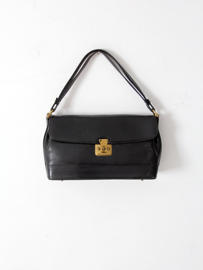Rolfs structured black leather shoulder bag with brass hardware 1970s: Rolfs structured black leather shoulder bag with brass hardware 1970s Vintage Rolfs shoulder bag from the 1970s in black leather with a structured silhouette. It features short double straps, brass ha