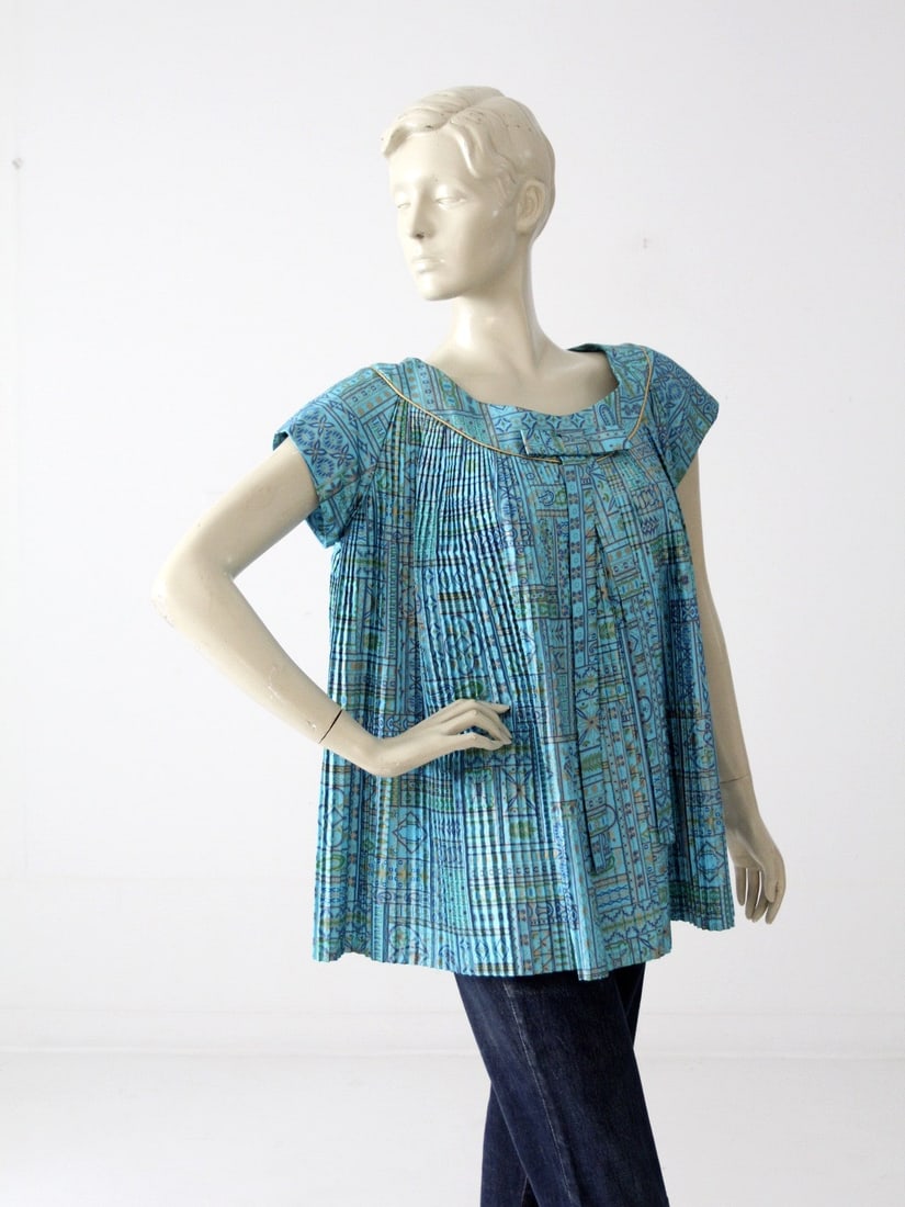 1960s Vintage Blue Satin Trapeze Blouse with Gold Print: 1960s Vintage Blue Satin Trapeze Blouse with Gold Print Step back in time with this stunning 1960s vintage trapeze blouse. Crafted from lush blue satin, this blouse features cap sleeves and a pleated 