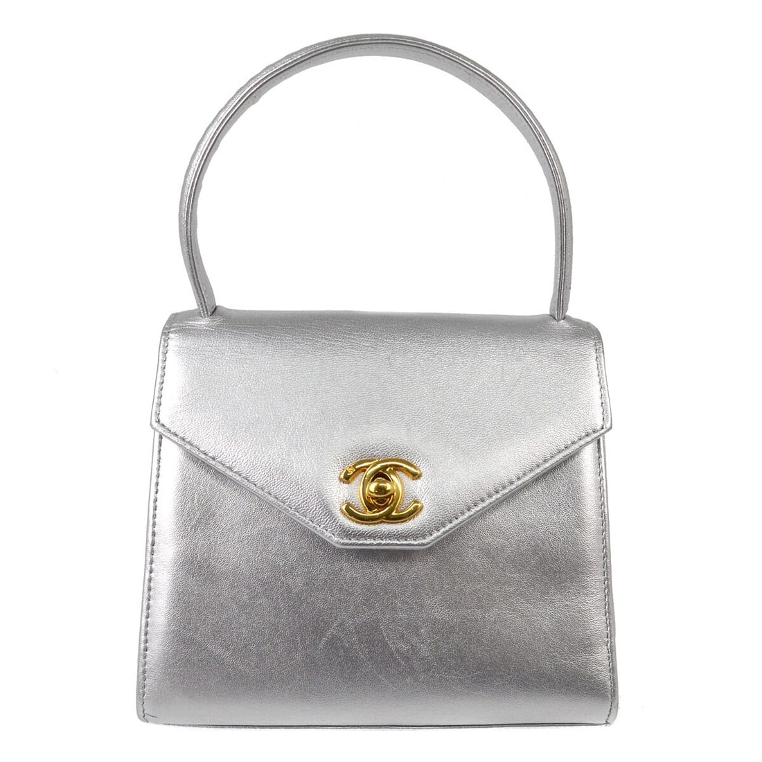 Mini top handle bag in silver lambskin by Chanel: Mini top handle bag in silver lambskin by Chanel Mini top handle handbag in silver lambskin with a turn-lock closure. The bag shows scuffs and scratches on the exterior, with scuffs and some stains in