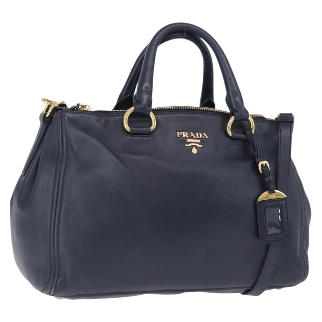 PRADA Navy Leather 2way Handbag with Shoulder Strap: PRADA Navy Leather 2way Handbag with Shoulder Strap Prada women's 2-way handbag in navy leather with gold-tone accents. Made in Romania, this bag includes a name tag and shoulder strap. Condition is B