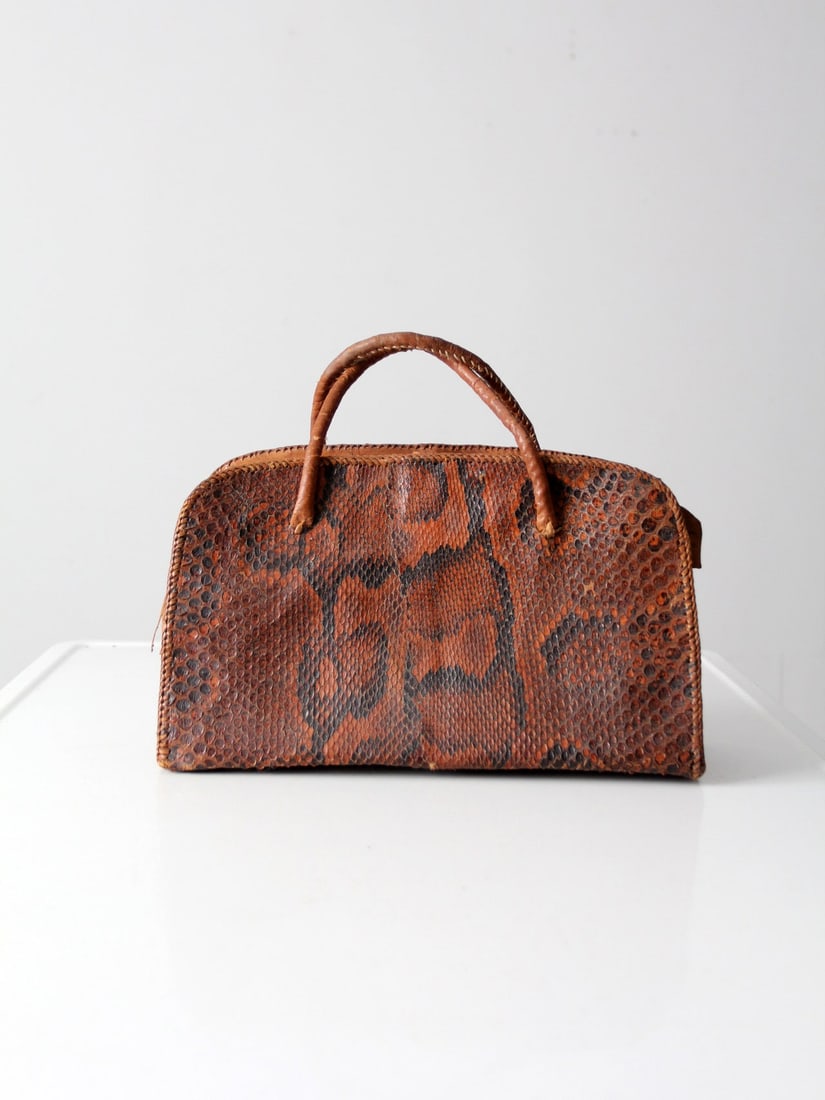 Chic Vintage Snakeskin Satchel Handbag with Leather Accents: Chic Vintage Snakeskin Satchel Handbag with Leather Accents Elevate your accessory collection with this Vintage Snakeskin Satchel. This chic handbag showcases a structured silhouette complemented by t
