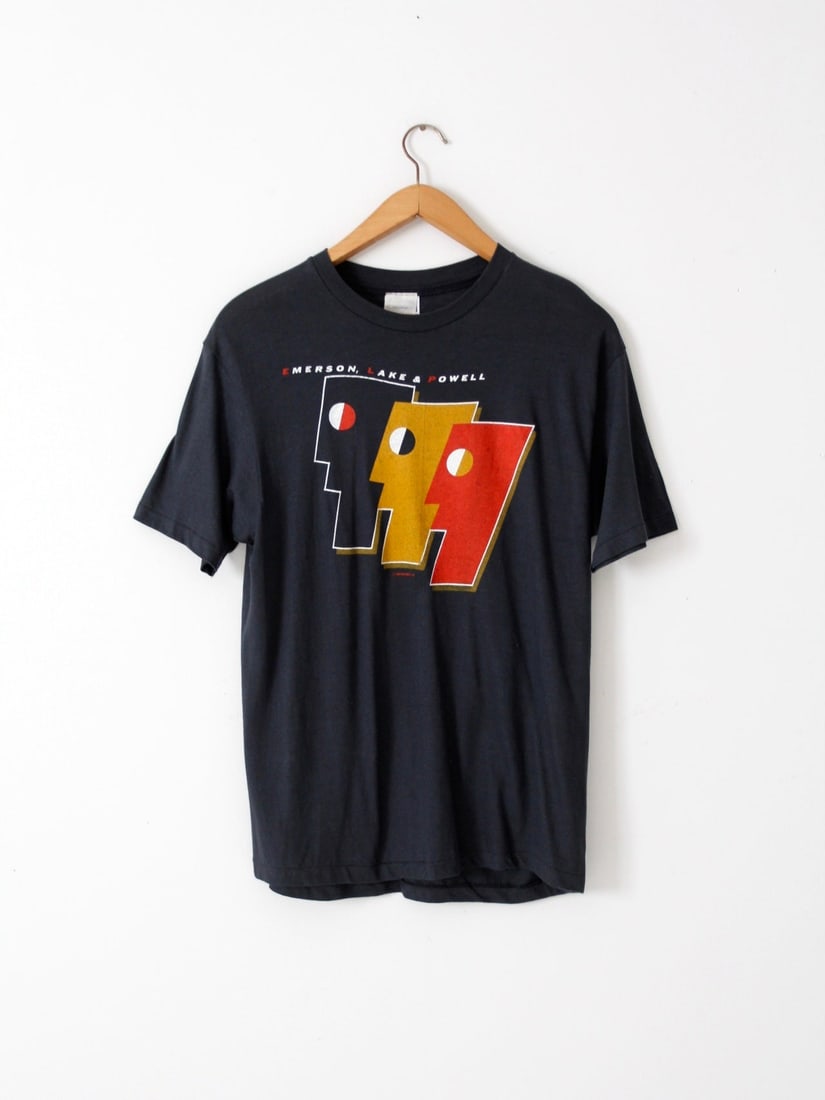 1980s Vintage Emerson Lake & Powell T-Shirt with Album Art: 1980s Vintage Emerson Lake & Powell T-Shirt with Album Art This vintage Emerson Lake & Powell t-shirt from the 1980s is a must-have for fans of the band. Made from 100% cotton, this black tee features