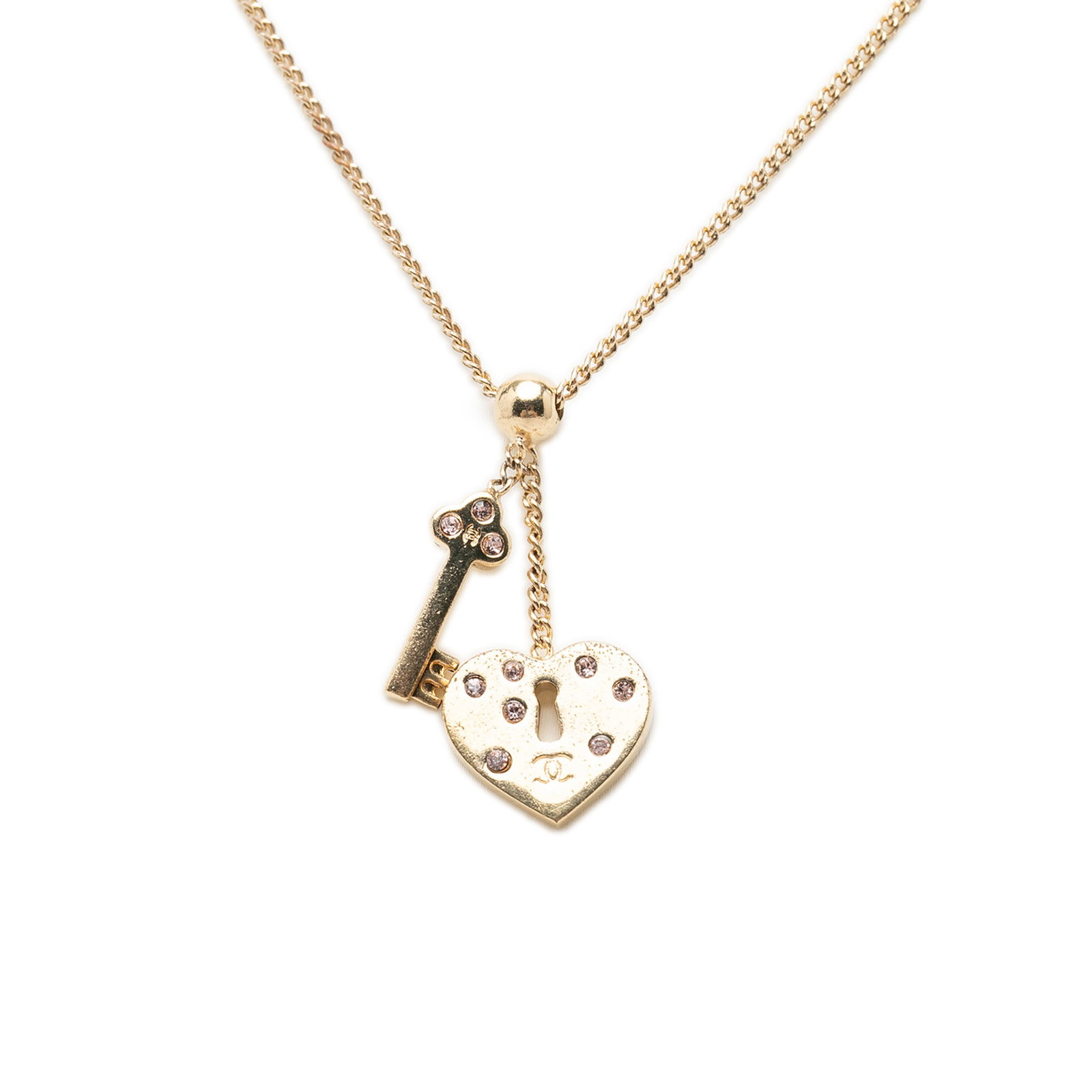 Chanel CC Heart Lock Key Pendant Necklace Gold Plated Strass: Chanel CC Heart Lock Key Pendant Necklace Gold Plated Strass Chanel CC pendant necklace featuring a gold-plated chain with heart lock and key pendants accented by strass embellishments. Finished with 