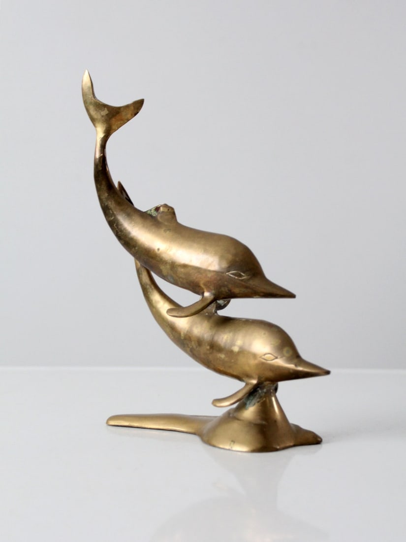 Mid-Century Solid Brass Dolphin Statue with Aged Patina: Mid-Century Solid Brass Dolphin Statue with Aged Patina This mid-century brass dolphin statue showcases a sleek and stylized design featuring two dolphins in motion. Crafted from solid brass, it boast