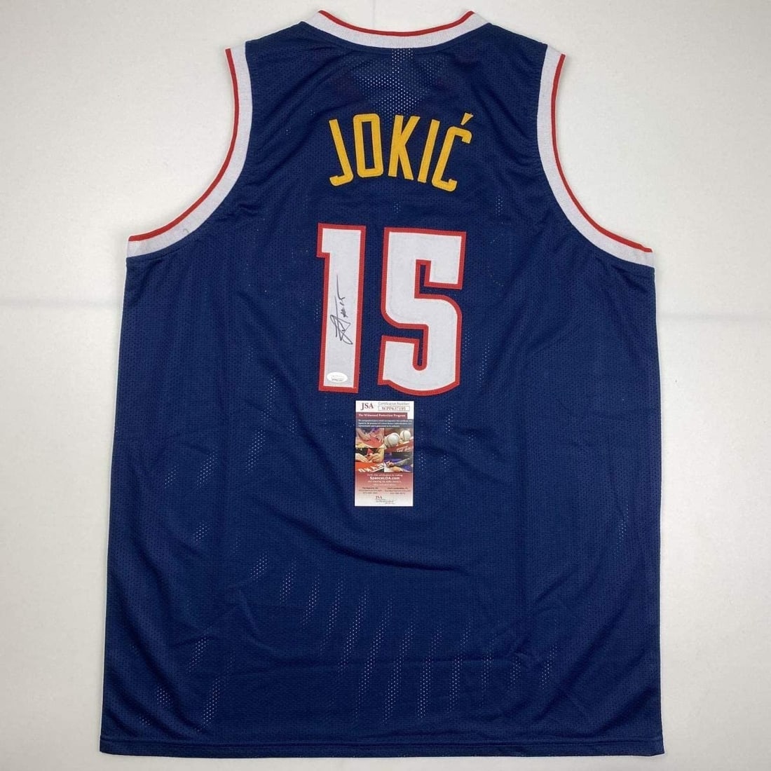 JSA Certified Nikola Jokic Signed Custom Blue Basketball Jersey XL: JSA Certified Nikola Jokic Signed Custom Blue Basketball Jersey XL Pre-owned custom dark blue basketball jersey signed by Nikola Jokic. Made as an autographed collectible, this original jersey feature