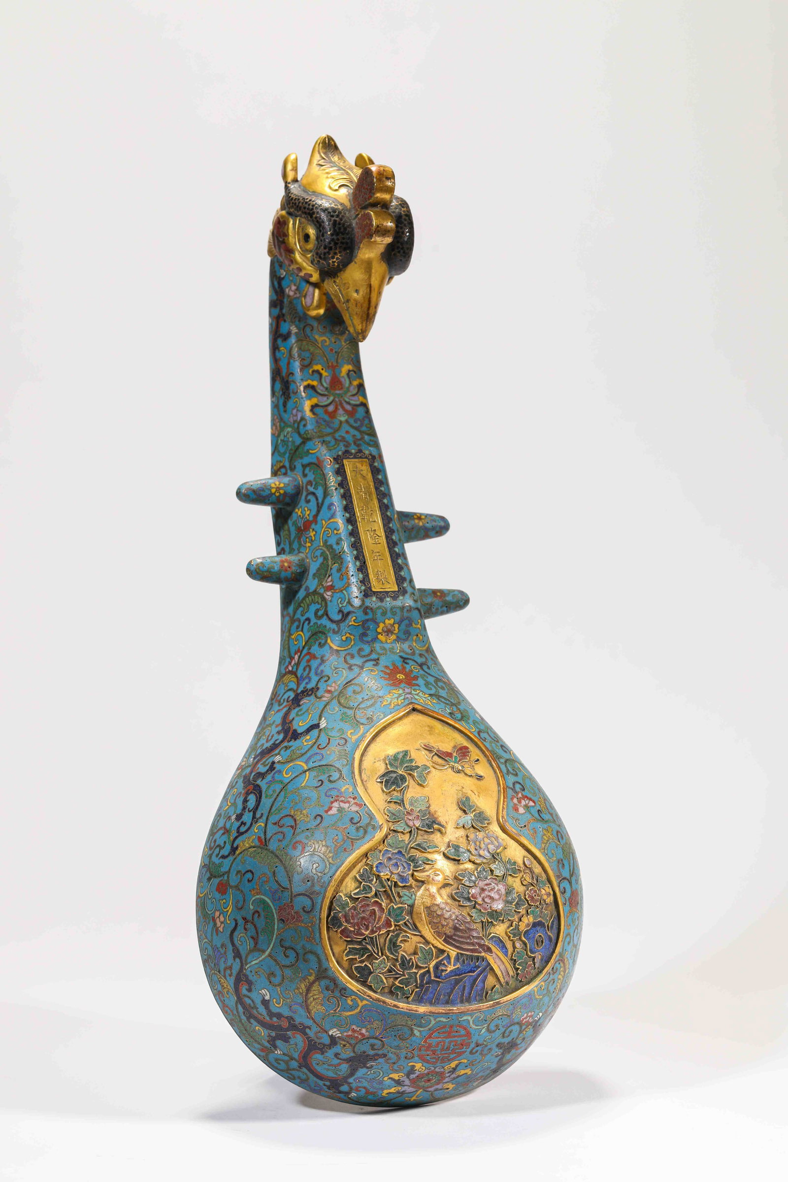A Cloisonné Enamel 'Floral Abundance' 'Phoenix-Head Lute-Form' Wall Vase: A CLOISONNÉ ENAMEL 'FLORAL ABUNDANCE' 'PHOENIX-HEAD LUTE-FORM' WALL VASE Dimensions: Dimensions: Weight: 1472 g. Length: 16.6 cm x Width: 8 cm x Height: 40.5 cm. All measurements are approximate.