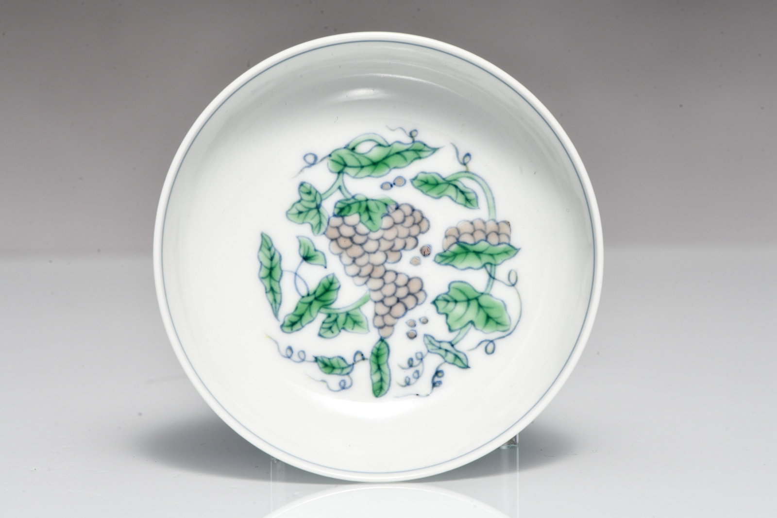 Celadon-glazed small plate with lotus-leaf pattern and grape design, made during the reign of: CELADON-GLAZED SMALL PLATE WITH LOTUS-LEAF PATTERN AND GRAPE DESIGN, MADE DURING THE REIGN OF EMPEROR CHENGHUA OF THE MING DYNASTY Description: Width: 8.2 cm Height: 2.5 cm