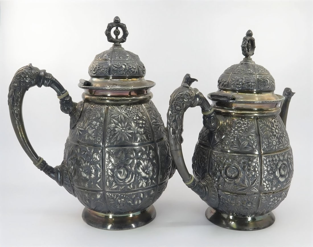 Repousse Silver Tea and Coffee Pots: REPOUSSE SILVER TEA AND COFFEE POTS Description: A pair of silver pots with raised floral and scroll decoration, hinged covers and sculptural handles. The images show the pair closed and open for