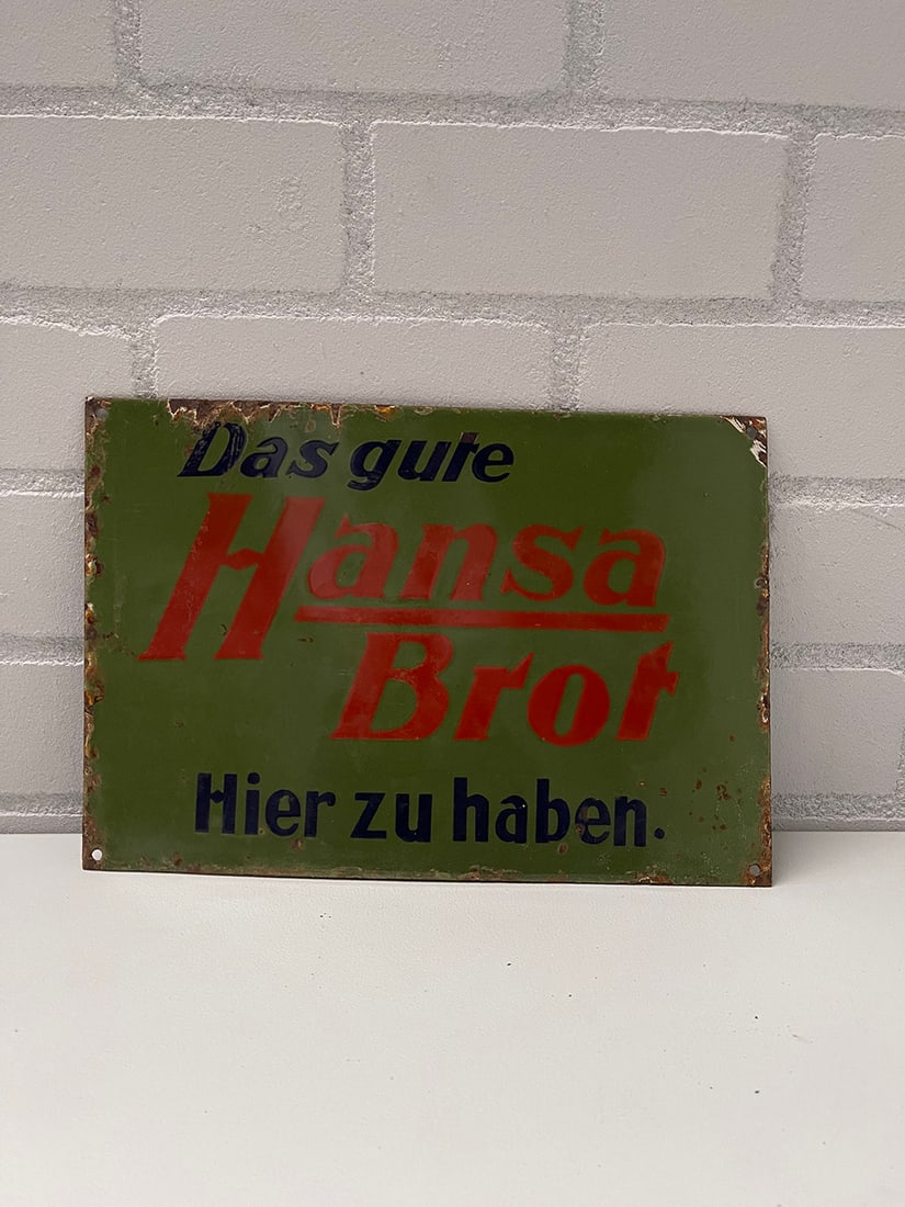 German Hansa Brot Enamel Sign: German Hansa Brot enamel sign. Overall fair condition, enamel loss on edges, some fading. Dimensions (H x W x D): 37 x 26 x 1 cm. Condition: Fair. Location: The Netherlands, Tilburg.