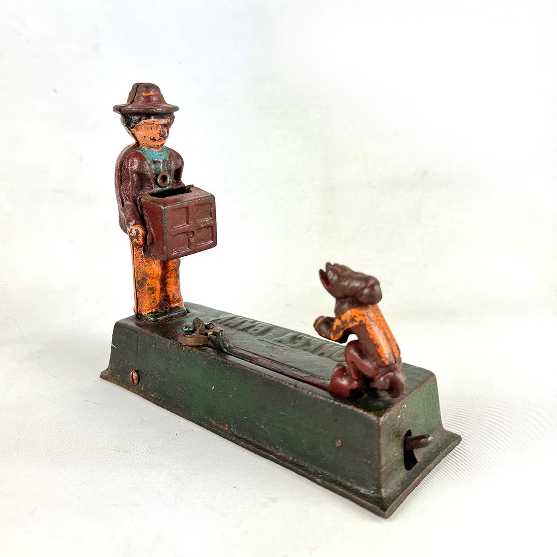 Antique Organ Grinder and Monkey Cast Iron Mechanical Bank: This Antique Organ Grinder and Monkey Cast Iron Mechanical Bank features a classic scene of a street performer and his trained monkey, a popular motif from the late 19th and early 20th centuries. The