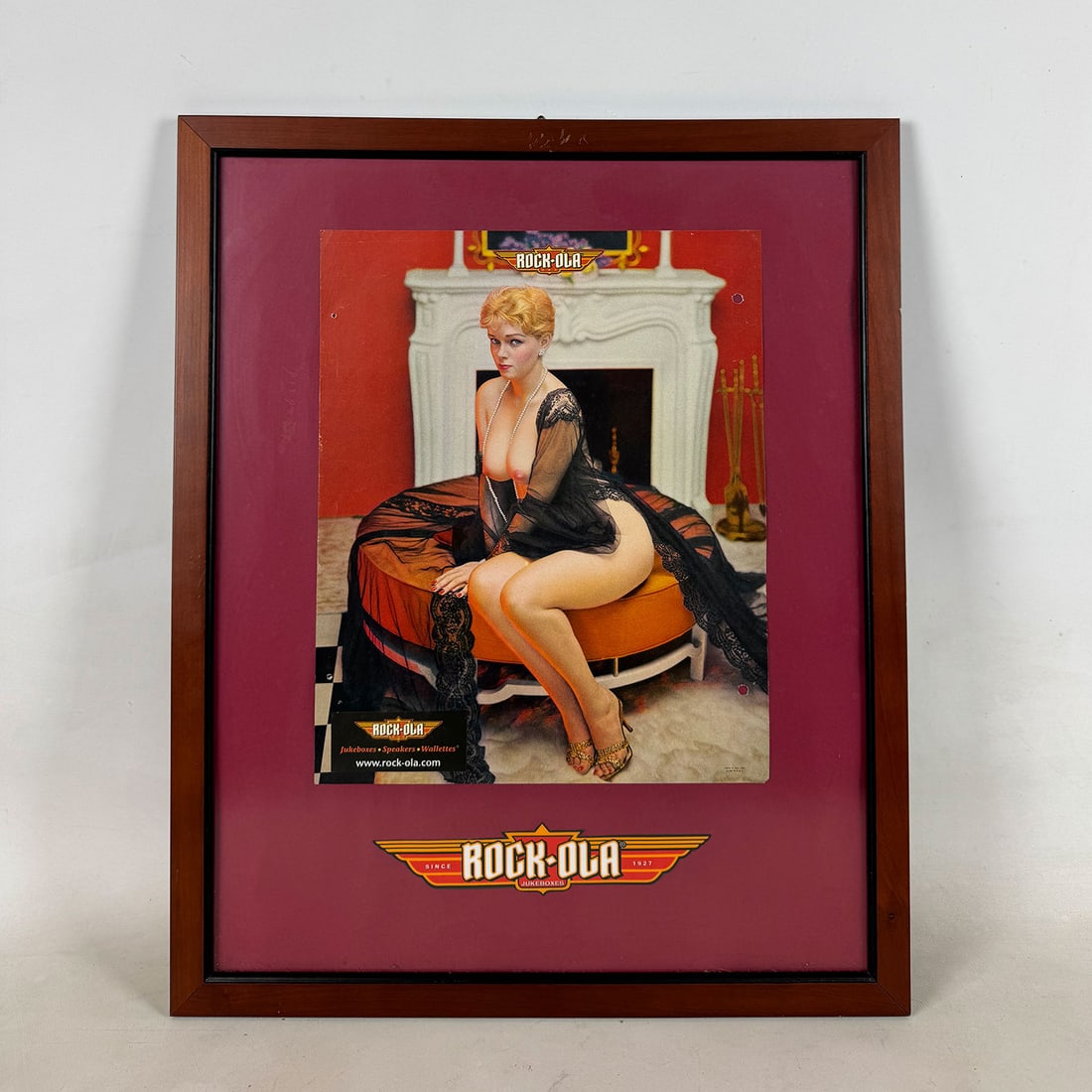 Framed Rock-Ola Erotic Art Advertisement: Framed Rock-Ola erotic art advertisement. Overall good condition the frame shows some wear and the advertisement has holes from previous binding or mounting. Dimensions (H x W x D): 55 x 45 x 2.5 cm. 