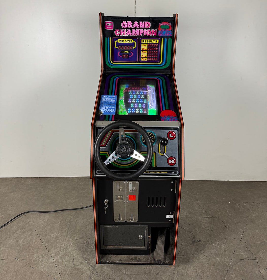 1981 Taito Grand Champion Compact Racing Video Game Arcade: 1981 Taito Grand Champion Compact racing video game arcade. A top-down vertical scrolling racing game. Compete against the other computer cars to win races. Visual condition: the cabinet is in good vi