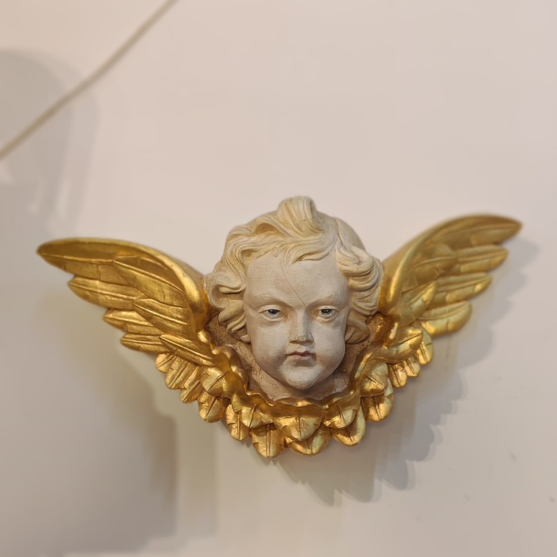 Plaster Cherub Mascaron with Gold Leaf Finished Wings: Plaster cherub mascaron with gold leaf finished wings, made from solid plaster, quite heavy. It has a hook for hanging on the back. Good visual condition, has a few small cracks on the face. Dimension