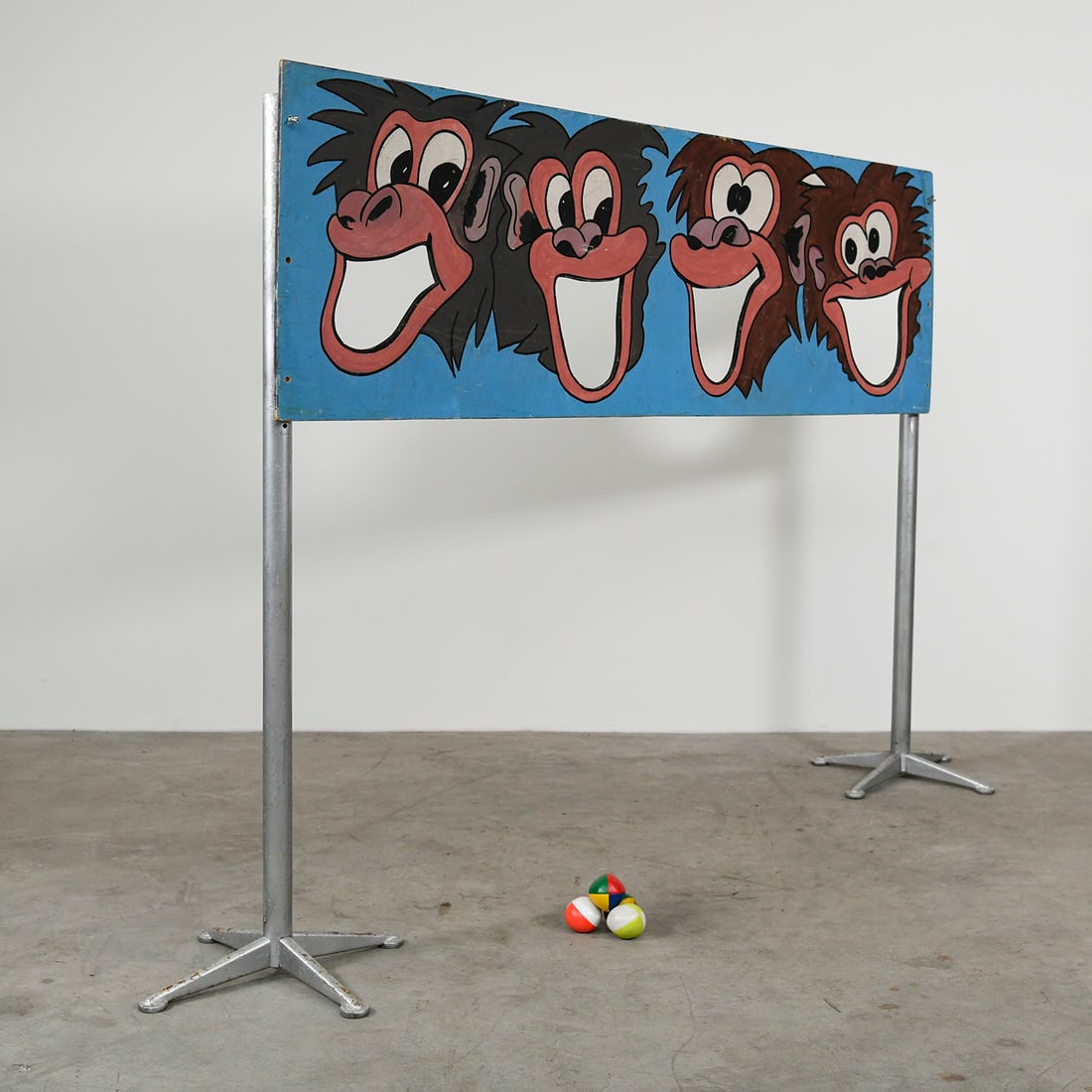 Vintage "Feed the Monkeys" Skill-Toss Carnival Game with 4 Balls: Vintage "Feed the Monkeys" carnival game skill-toss attraction featuring a hand-painted wooden panel and a set of 4 balls. The game board displays four stylized monkey faces, each with a wide, cutout