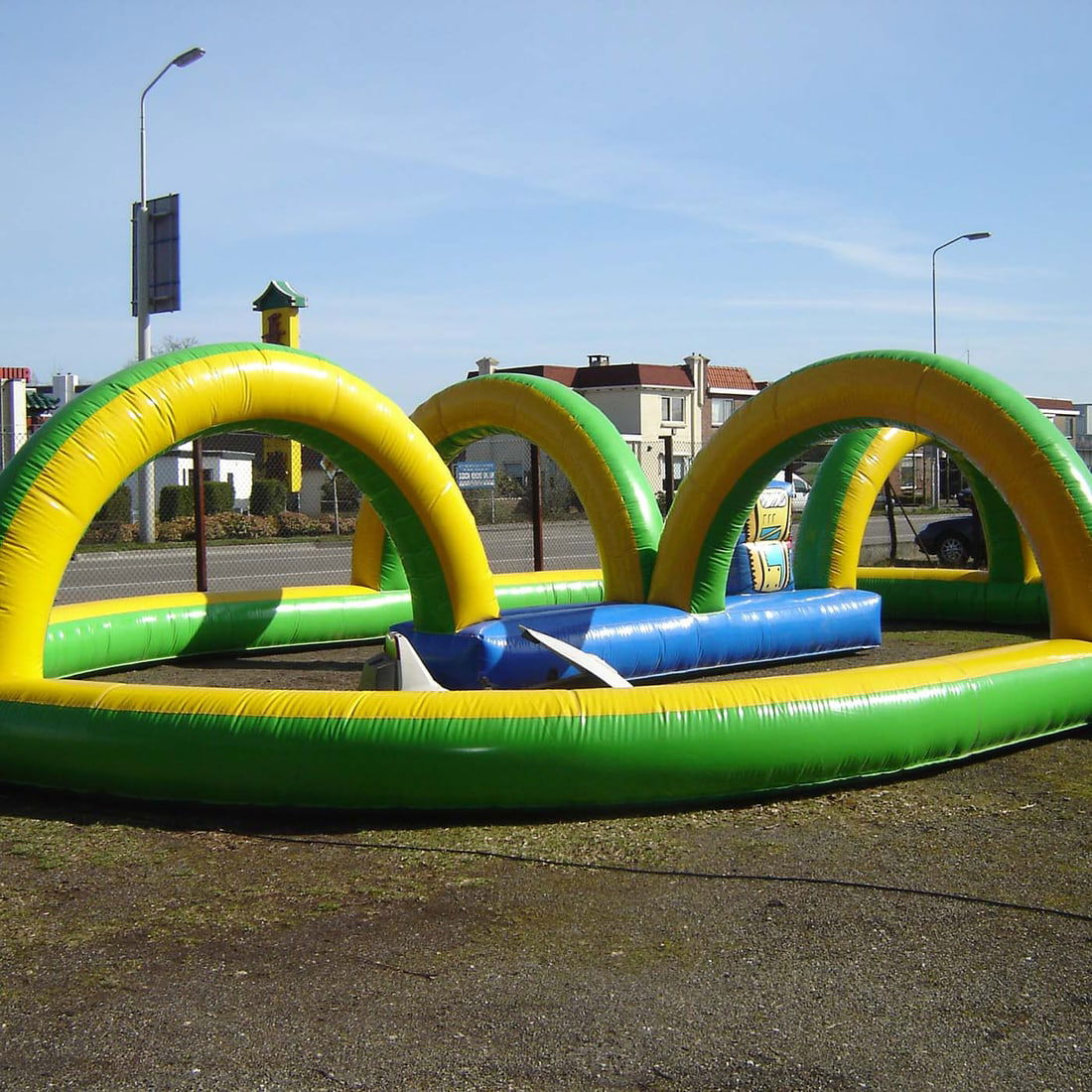 Yellow and Green Inflatable Racetrack for Children's Scooters, Go-karts or Mini-bikes: Vibrant yellow and green inflatable racetrack provides a safe and defined course for children's scooters, go-karts, or mini-bikes. The design features a cushioned perimeter wall and large overhead arc