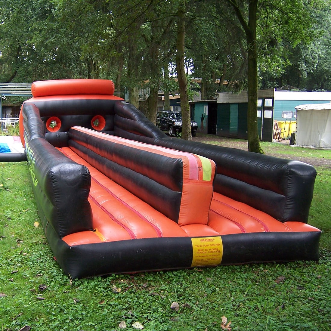 Commercial-grade Inflatable "Bungee Run" in Black and Orange: Commercial-grade inflatable "Bungee Run" made from durable PVC in black and orange. Features a long single-lane track with high side walls for safety and a center divider. Comes with black storage cra