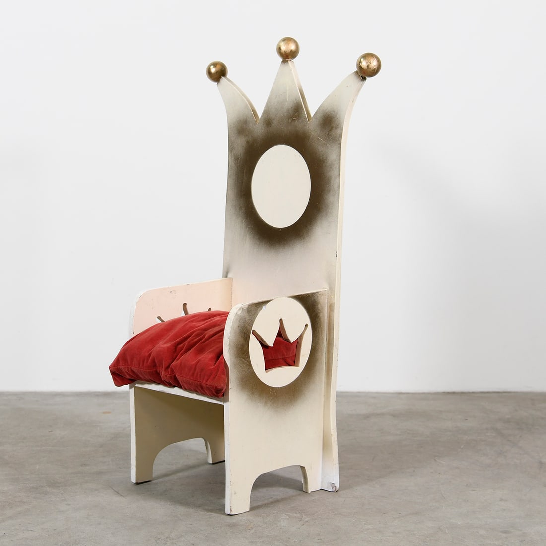Wooden Children's Throne with a Red Velvet Cushion: The children's throne is a whimsical, wooden chair designed for a young child, featuring a tall backrest carved into a three-pointed crown topped with gold-colored spheres. For comfort, the seat is fi