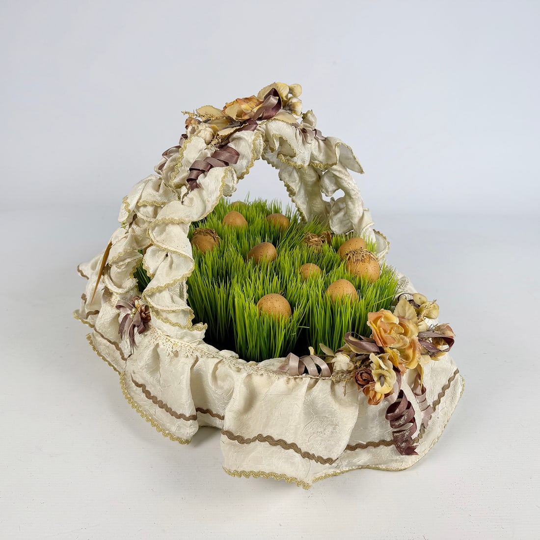 Decorative Easter Basket Srrangement Featuring Artificial Grass and Decorative Eggs: Decorative Easter basket arrangement featuring artificial grass and decorative eggs, finished with fabric ribbons and floral ornaments. Suitable as a seasonal decorative centerpiece. Very good used vi